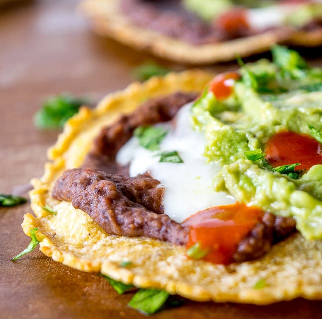 Serious reward to effort ratio in these tostadas! We're crisping a corn tortilla and loading it up with spicy black bean puree and a refreshing guacamole. So good! mexicanplease.com