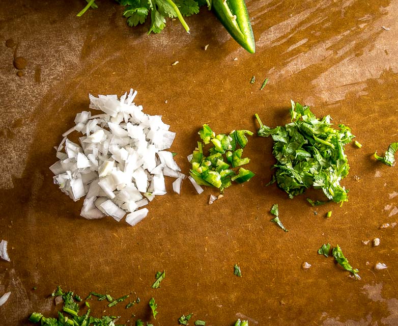 We're grinding an onion-jalapeno-cilantro paste in a molcajete for a delicious batch of homemade guacamole. Don't forget a final squeeze of lime, so good! mexicanplease.com