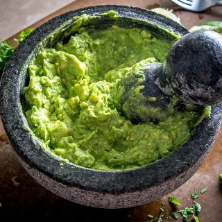 We're grinding an onion-jalapeno-cilantro paste in a molcajete for a delicious batch of homemade guacamole. Don't forget a final squeeze of lime, so good! mexicanplease.com