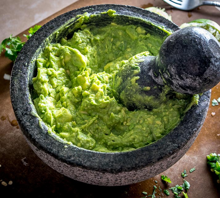 We're grinding an onion-jalapeno-cilantro paste in a molcajete for a delicious batch of homemade guacamole. Don't forget a final squeeze of lime, so good! mexicanplease.com