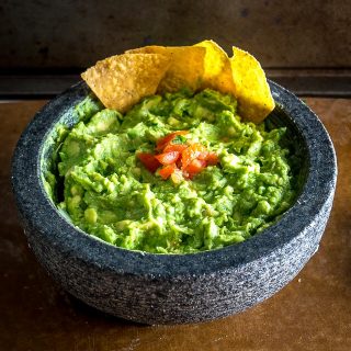 We're grinding an onion-jalapeno-cilantro paste in a molcajete for a delicious batch of homemade guacamole. Don't forget a final squeeze of lime, so good! mexicanplease.com