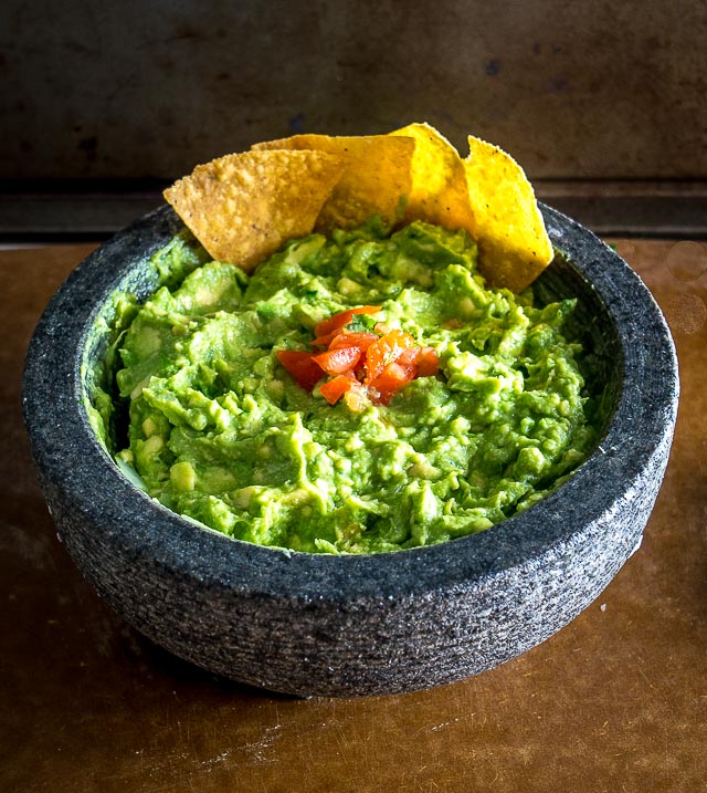 We're grinding an onion-jalapeno-cilantro paste in a molcajete for a delicious batch of homemade guacamole. Don't forget a final squeeze of lime, so good! mexicanplease.com