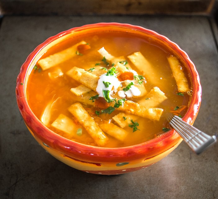 https://www.mexicanplease.com/wp-content/uploads/2017/11/chicken-tortilla-soup-adding-to-a-bowl-crema.jpg