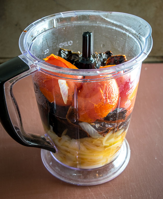 Adding enchilada sauce ingredients to a blender.