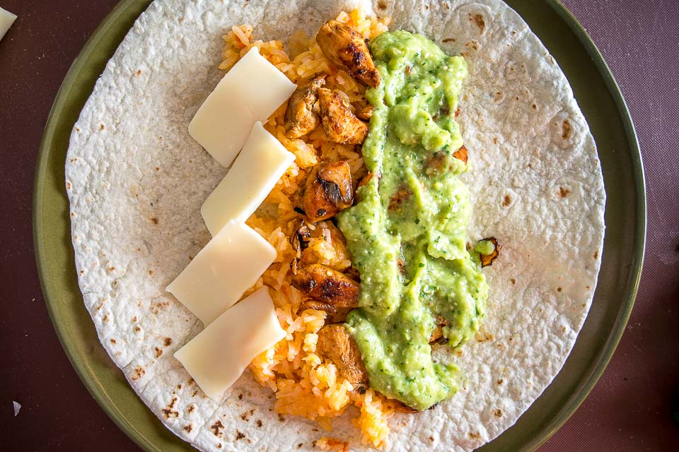 Put some Avocado Salsa Verde in your burritos and everything beyond that is a bonus! I added chicken, Mexican rice, and cheese to this batch -- yum!! mexicanplease.com