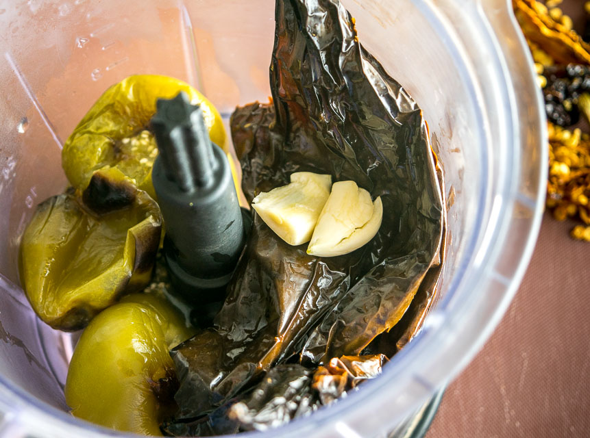 Adding tomatillos and pasillas to a blender for salsa