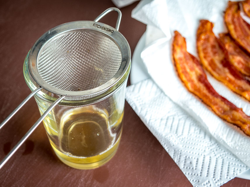 Adding bacon drippings to a jar. 