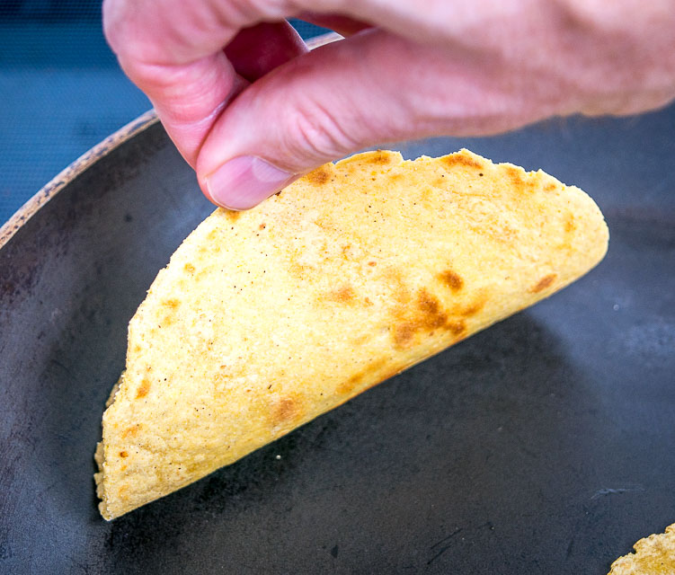 Checking underneath corn tortilla for light brown spots.
