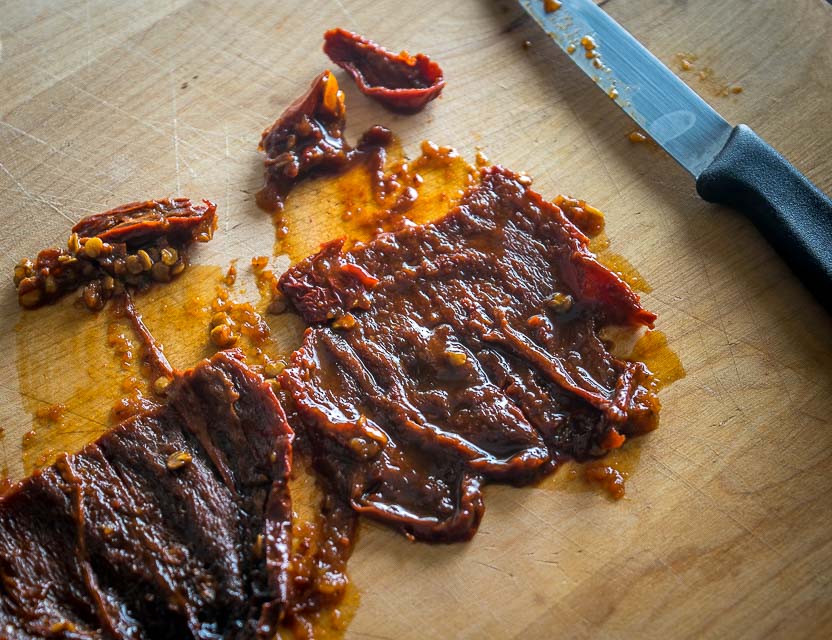 Scraping out seeds of chipotles in adobo.