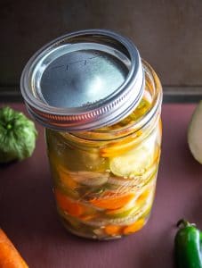 Quart sized Mason jar of pickled jalapenos, tomatillos, onions, and carrots.