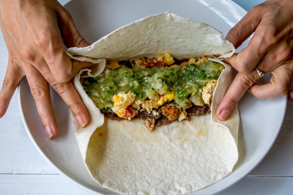 Step 4:  Use your fingers to hold the sides in place as you grab the bottom of the tortilla with your thumbs and fold it over the fillings.