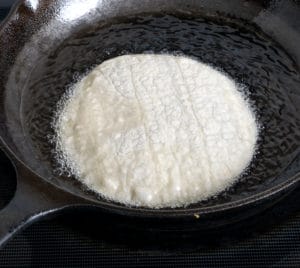 Corn tortilla frying in hot oil
