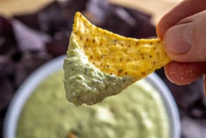 Dipping a chip in Roasted Poblano Queso Dip