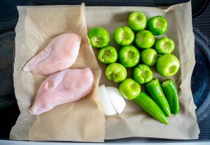 Adding chicken and tomatillos to baking sheet for roasting