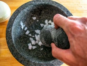 Grinding onion and salt in a molcajete