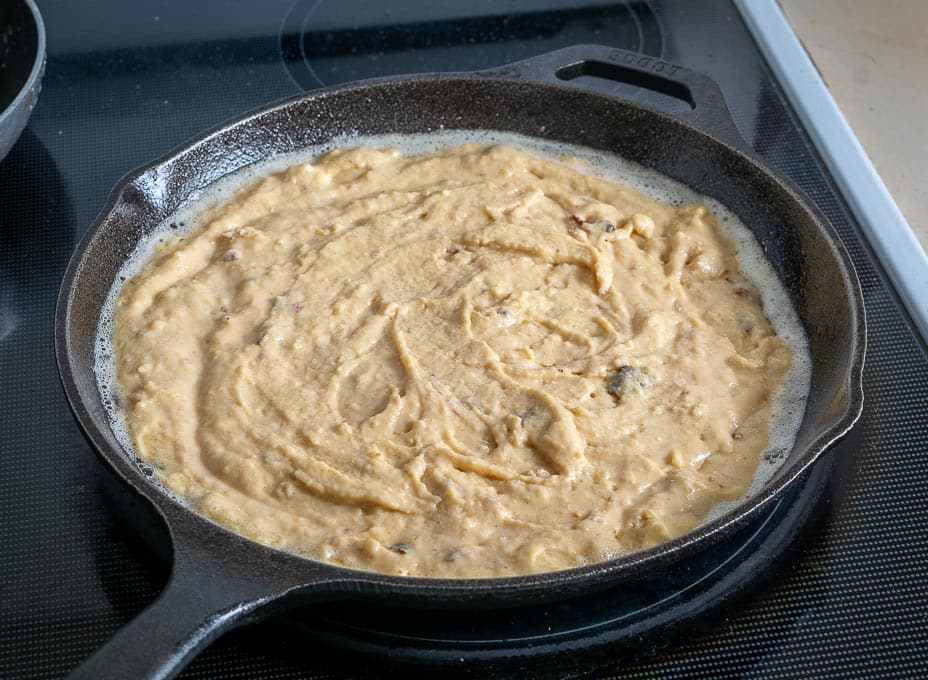 Hinzufügen von Maisbrotmischung zu einer Gusseisenpfanne