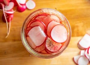 Mason jar of sliced radishes filled to the brim with brine