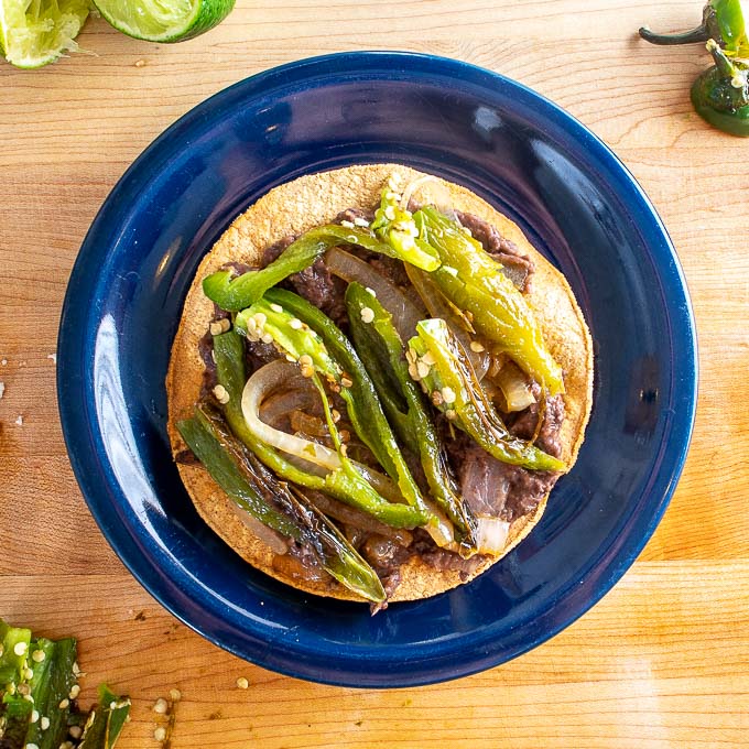 Adding sliced up Chile Toreados to the refried beans