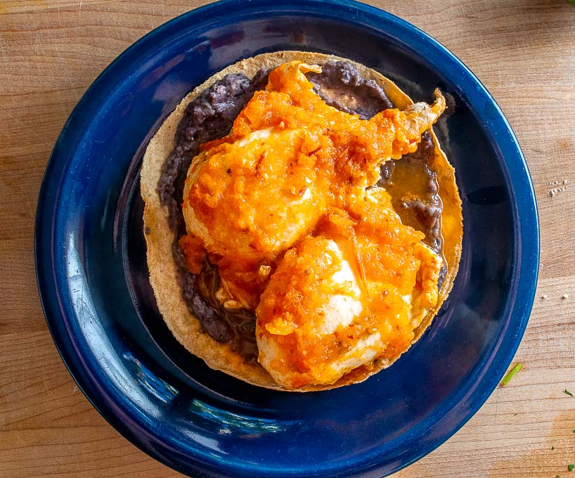 Adding poached eggs to the tostada