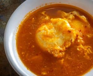 Poached egg resting in salsa broth