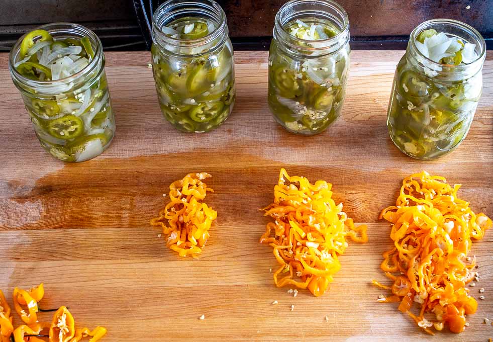 4 pint sized jars of Pickled Jalapenos along with chopped Habaneros