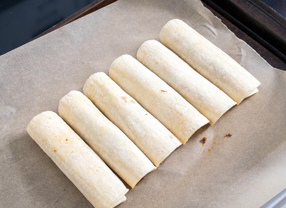 Six taquitos on baking sheet before going into the oven
