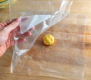Adding golfball sized round of masa dough to Ziploc bag