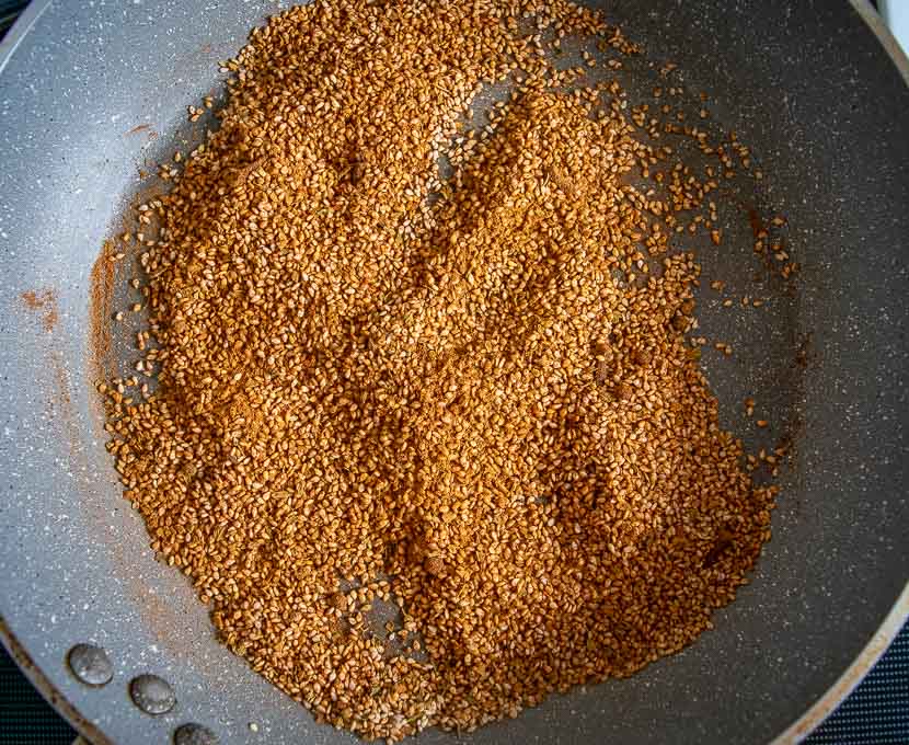 Adding cinnamon and Mexican oregano to the roasting sesame seeds