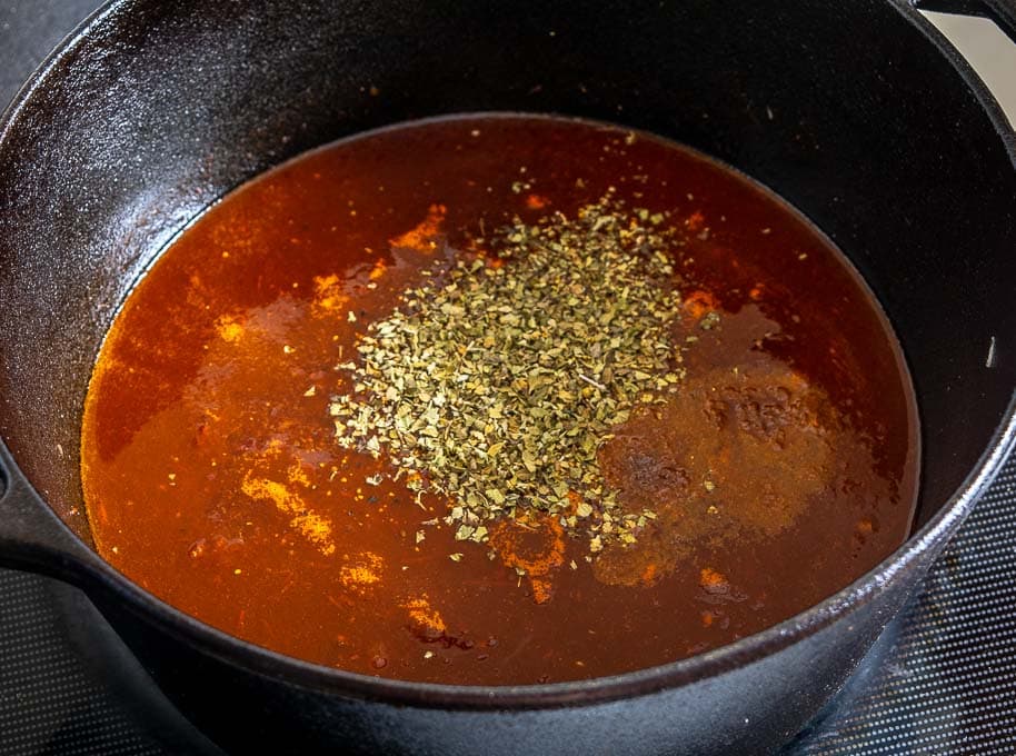 Adding Mexican oregano to the soup pot