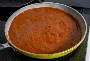 Adding Mole sauce to a large saucepan