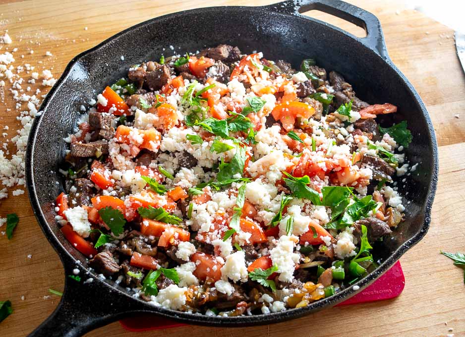 Topping with Queso Fresco, tomatoes, cilantro and lime juice