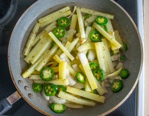 Adding drained potatoes and jalapenos to the pan