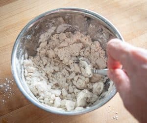 Using spoon to combine lard with flour