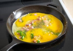 Adding six whisked eggs to the pan