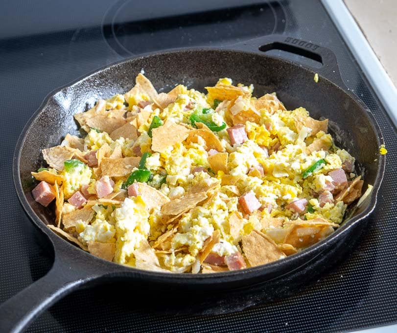 Adding crumbled corn tortillas to the Migas