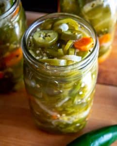 Adding jalapenos to Mason jars and filling with brine