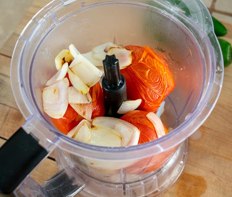 Adding tomatoes, onion and garlic to the blender