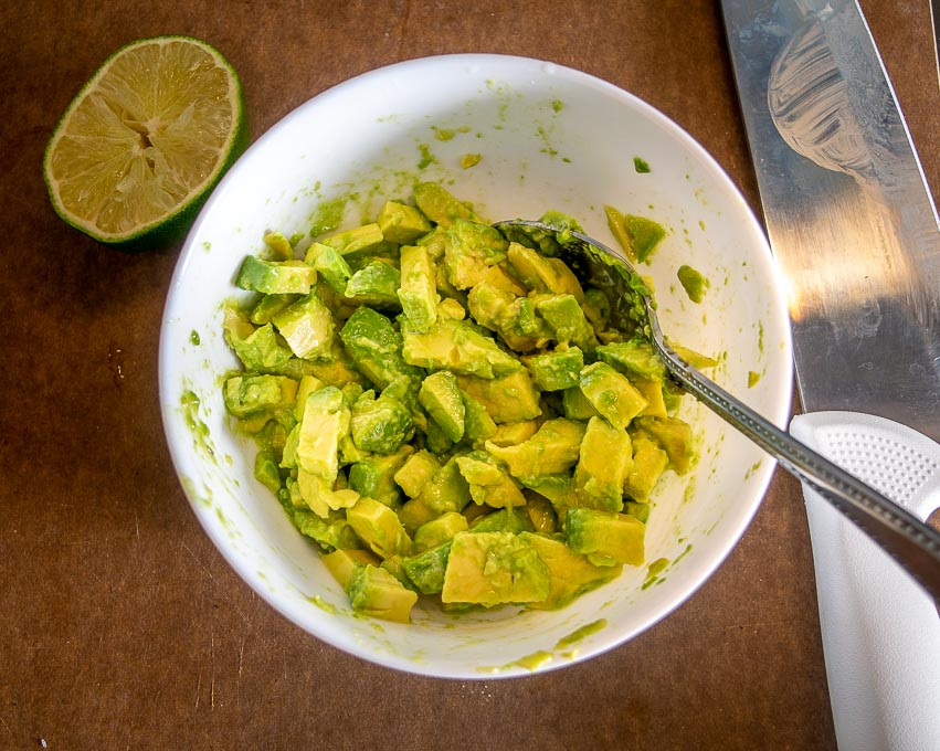 Dressing raw avocado bits with lime and salt
