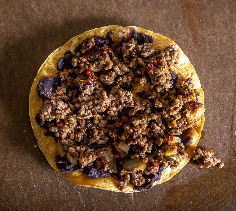 Adding ground beef mixture to the tostada