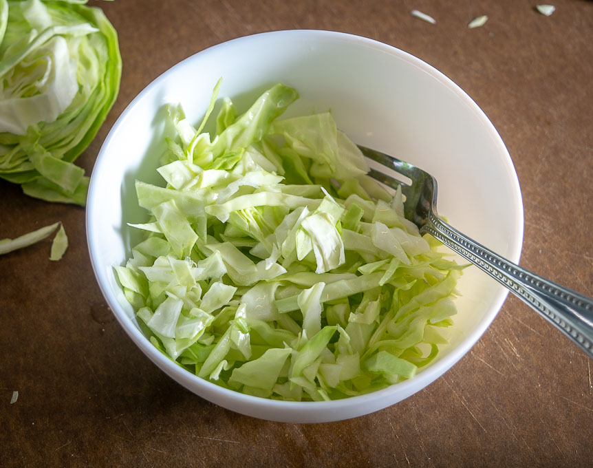 Tossing thinly sliced cabbage with lime juice