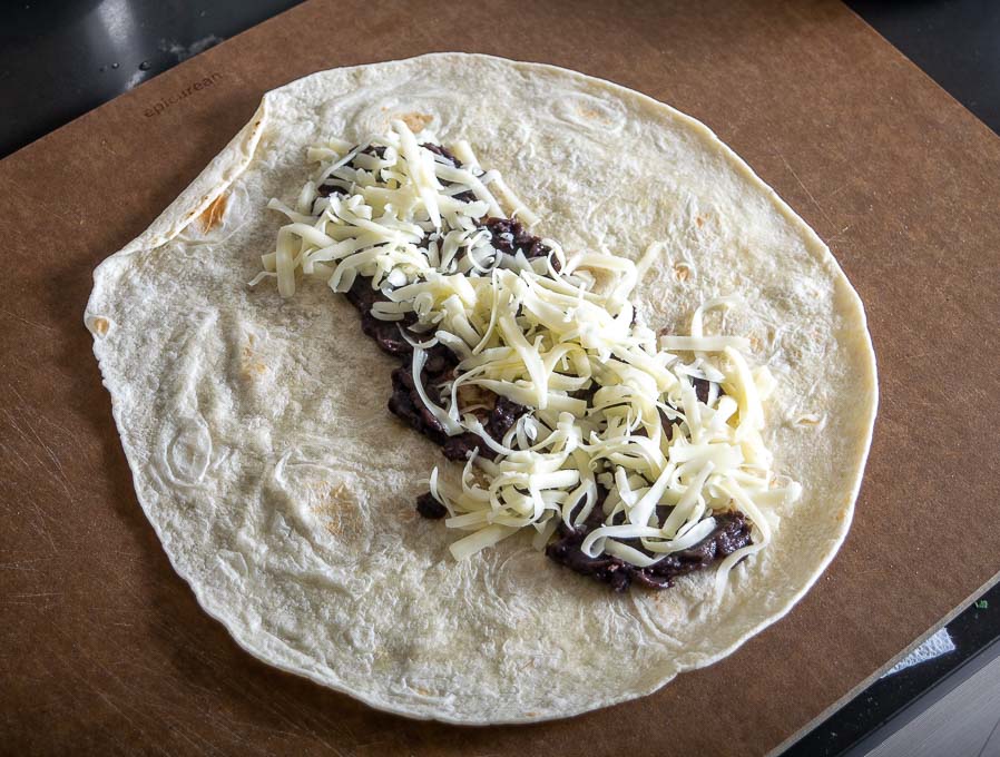 Adding beans and cheese to the flour tortilla