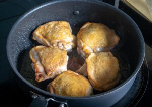 Browning chicken thighs before cooking arroz con pollo