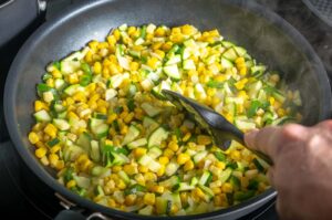 Cooking the zucchini and corn in the pan.