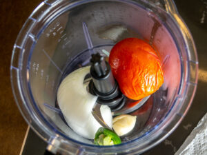 Adding ingredients for the tomato-jalapeno mixture to the blender