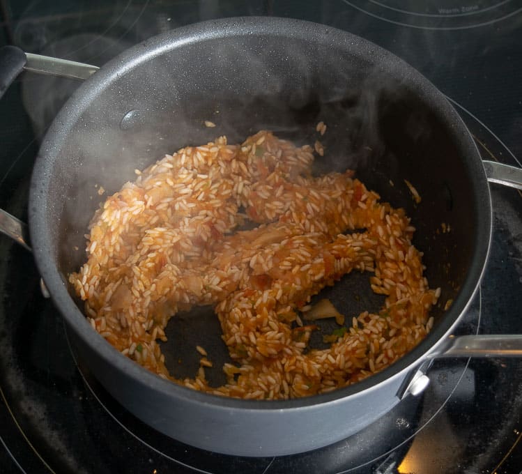 Adding tomato-jalapeno mixture to the rice