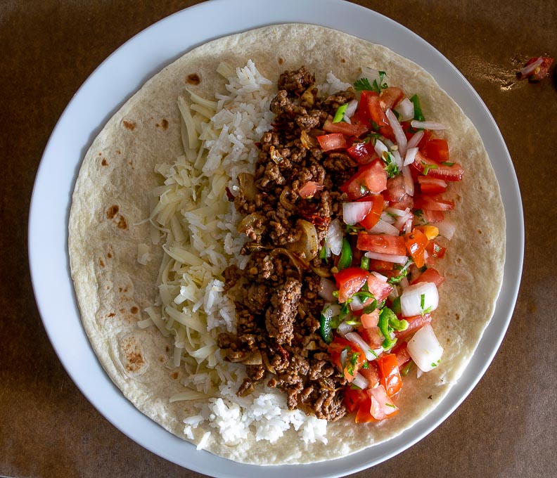 Adding all the fixings to a warmed up flour tortilla