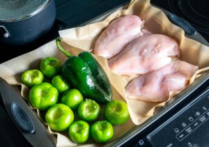 Adding chicken, tomatillos, and poblano to baking sheet for roasting