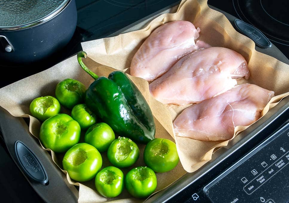 Adding chicken, tomatillos, and poblano to baking sheet for roasting