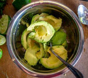 Adding flesh of five avocados to the mixing bowl