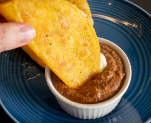 Dipping some cheesy, crispy corn tortillas in the bean dip